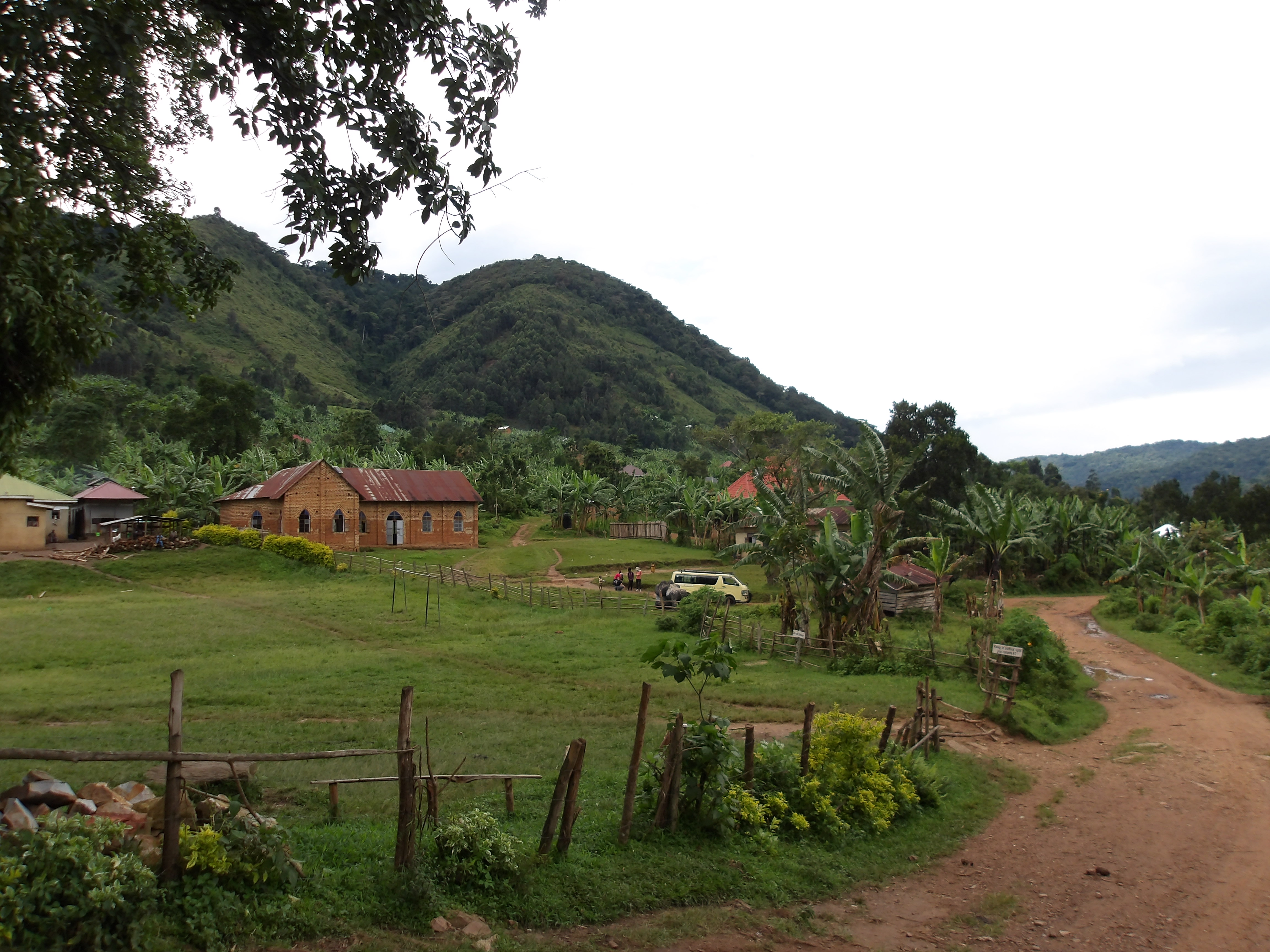 a church in a grassy field next to a dirt road and green hills