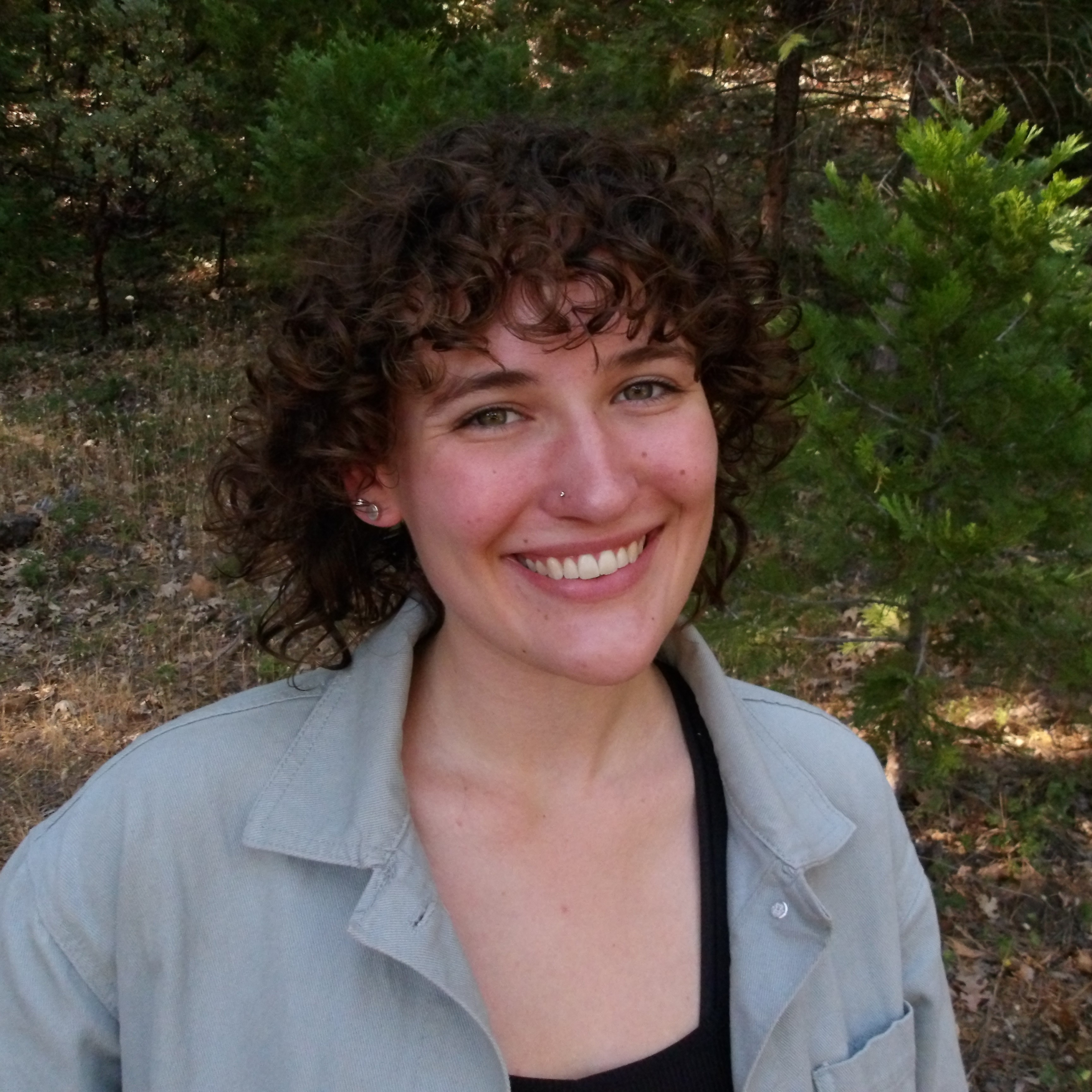 emily smiling standing in front of trees and bushes