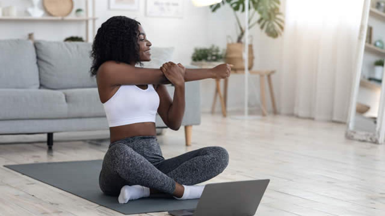 woman stretching in front of computer screen at home