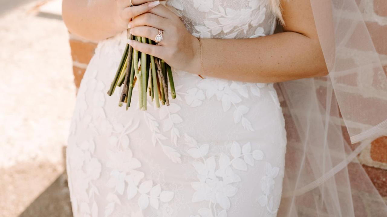 Andrea in a wedding dress smiling through flowers