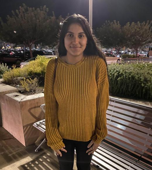 Nimra wearing a yellow sweater and smiling