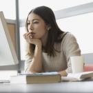 Woman staring at computer leaning face on hand